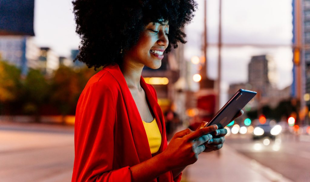 Beautiful young happy african woman with afro curly hairstyle strolling in the city - Cheerful black student girl walking on the street in the evening