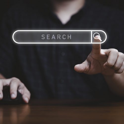 Hand touching to virtual search icon to SEO or search Engine Optimisation for marketing and consumer information concept.
