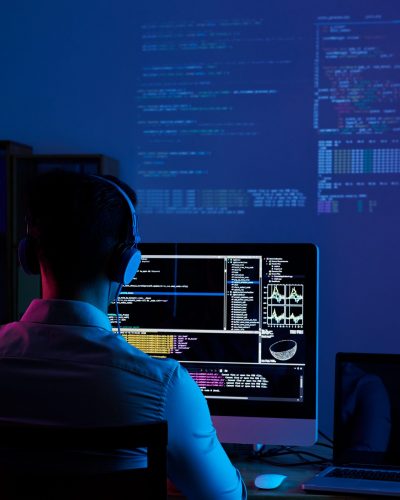 Developer working on code late at night, view from the back